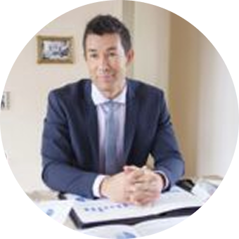 Man in suit sitting at desk, smiling.